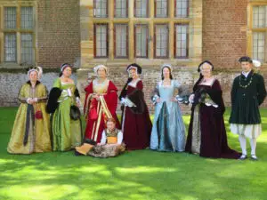 From the right – George Boleyn, Katherine of Aragon [English hood], Anne Boleyn [French hood], Jane Seymour [English hood], Anne of Cleves [German style headdress], Katherine Howard [French hood] and Katherine Parr [a cap and hat]. Seated – Princess Elizabeth.
By kind permission of the Tudor Queens, taken at Penshurst Place, Kent [GRM 2021]. 